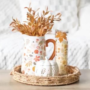 Autumn leaves and pumpkins ceramic flower jug and tube candle in a wicker basket tray